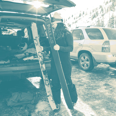 Image of a woman prepping her Pallas splitboard at her vehicle in the parking lot before heading int the backcountry.