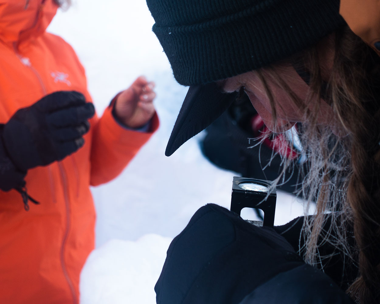 Pallas rider Sid Garrido examining snow crystals on a heli snowboard trip in Canada