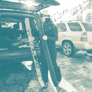 Image of a woman transitioning her Pallas splitboard into ski mode and gearing up in the parking lot before venturing into the backcountry.
