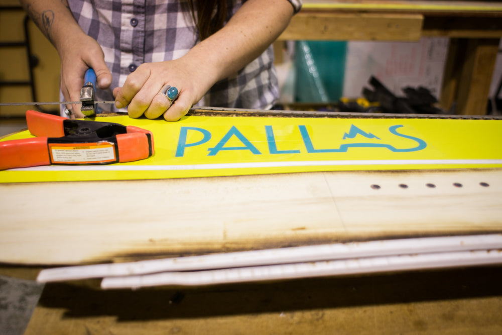 A snowboard builder works on laying up a Pallas splitboard in the workshop before it goes into the snowboard press.